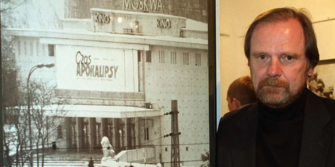 Mężczyzna z brodą obok plakatu kina "Moskwa" z napisem "Czas Apokalipsy".