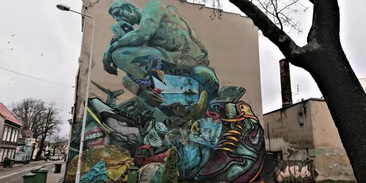 Co to jest mural? Ogromna, surrealistyczna grafika na ścianie budynku, przedstawiająca myślącą postać, krajobraz morski, jedzenie i przedmioty codziennego użytku.