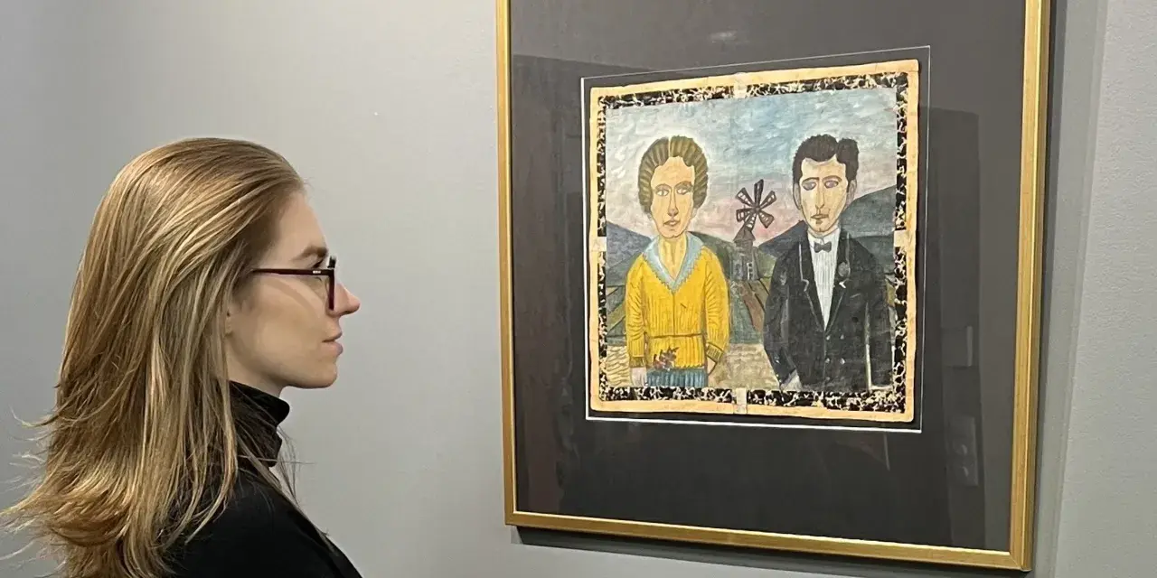 Kobieta w okularach podziwia obraz Nikifora z parą w strojach ślubnych. Czy to najdroższy obraz Nikifora?