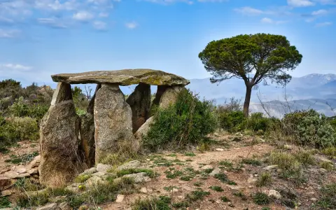 Starożytny menhir, kamienna konstrukcja, stoi na wzgórzu pod błękitnym niebem.
