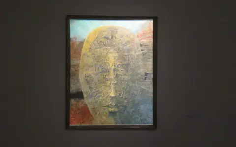 Jedna z najsłynniejszych obrazów Beksińskiego: surrealistyczna, złocista twarz wyłaniająca się z mroku, pełna tajemniczych detali.