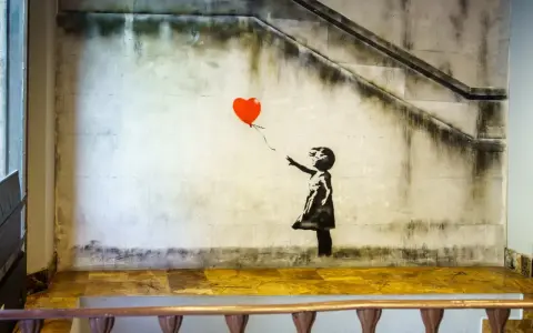 Banksy dziewczynka z balonikiem, unoszącym się na tle schodów i zniszczonej ściany.