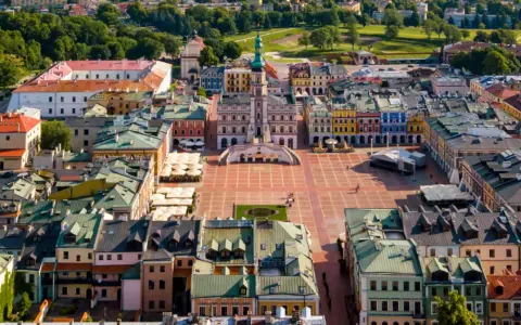 Zamość miasto idealne: renesansowy rynek z kolorowymi kamienicami i ratuszem, otoczony zielenią.