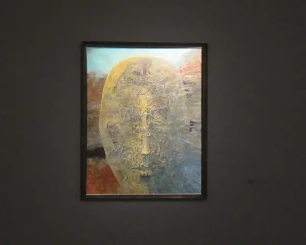 Jedna z najsłynniejszych obrazów Beksińskiego: surrealistyczna, złocista twarz wyłaniająca się z mroku, pełna tajemniczych detali.