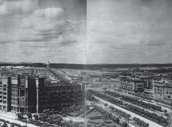 Rozległe osiedle z charakterystyczną **sowiecką architekturą**, zdominowane przez wielopiętrowe budynki mieszkalne i przemysłowe, z alejami drzew wzdłuż ulic.