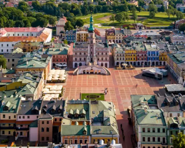 Zamość miasto idealne: renesansowy rynek z kolorowymi kamienicami i ratuszem, otoczony zielenią.