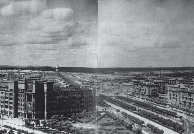 Rozległe osiedle z charakterystyczną **sowiecką architekturą**, zdominowane przez wielopiętrowe budynki mieszkalne i przemysłowe, z alejami drzew wzdłuż ulic.