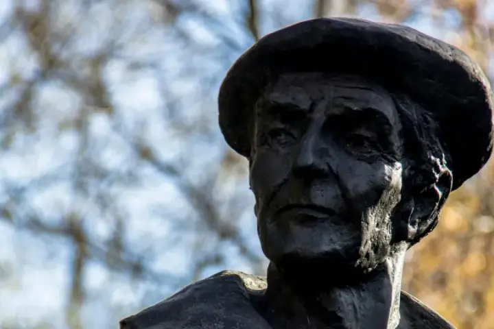 Portret rzeźbiarski w ciemnym brązie, ukazujący twarz mężczyzny w beretce. Widać głębokie zmarszczki i wyraziste rysy, oddające estetykę dzieł Kenara.