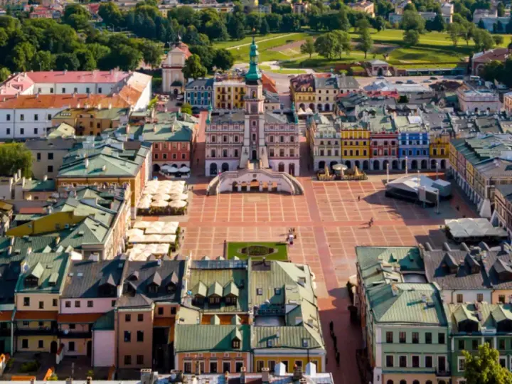 Zamość miasto idealne: renesansowy rynek z kolorowymi kamienicami i ratuszem, otoczony zielenią.