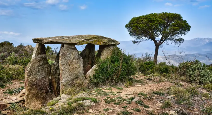 Starożytny menhir, kamienna konstrukcja, stoi na wzgórzu pod błękitnym niebem.