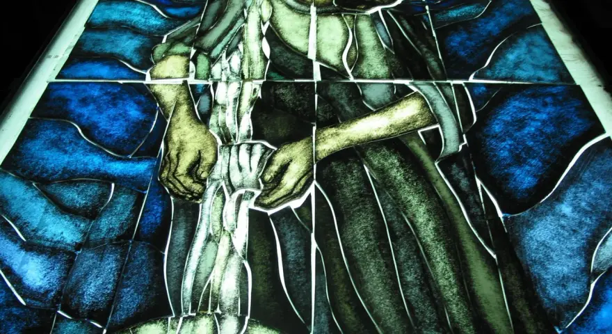 Fragment witrażu w stylu modernizm, przedstawiający postać w niebieskim i zielonym tle.