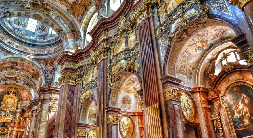 Bogata architektura baroku zachwyca złotymi zdobieniami, marmurowymi kolumnami i freskami na sklepieniach.
