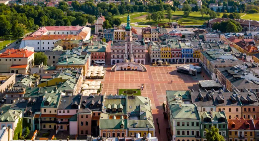 Zamość miasto idealne: renesansowy rynek z kolorowymi kamienicami i ratuszem, otoczony zielenią.