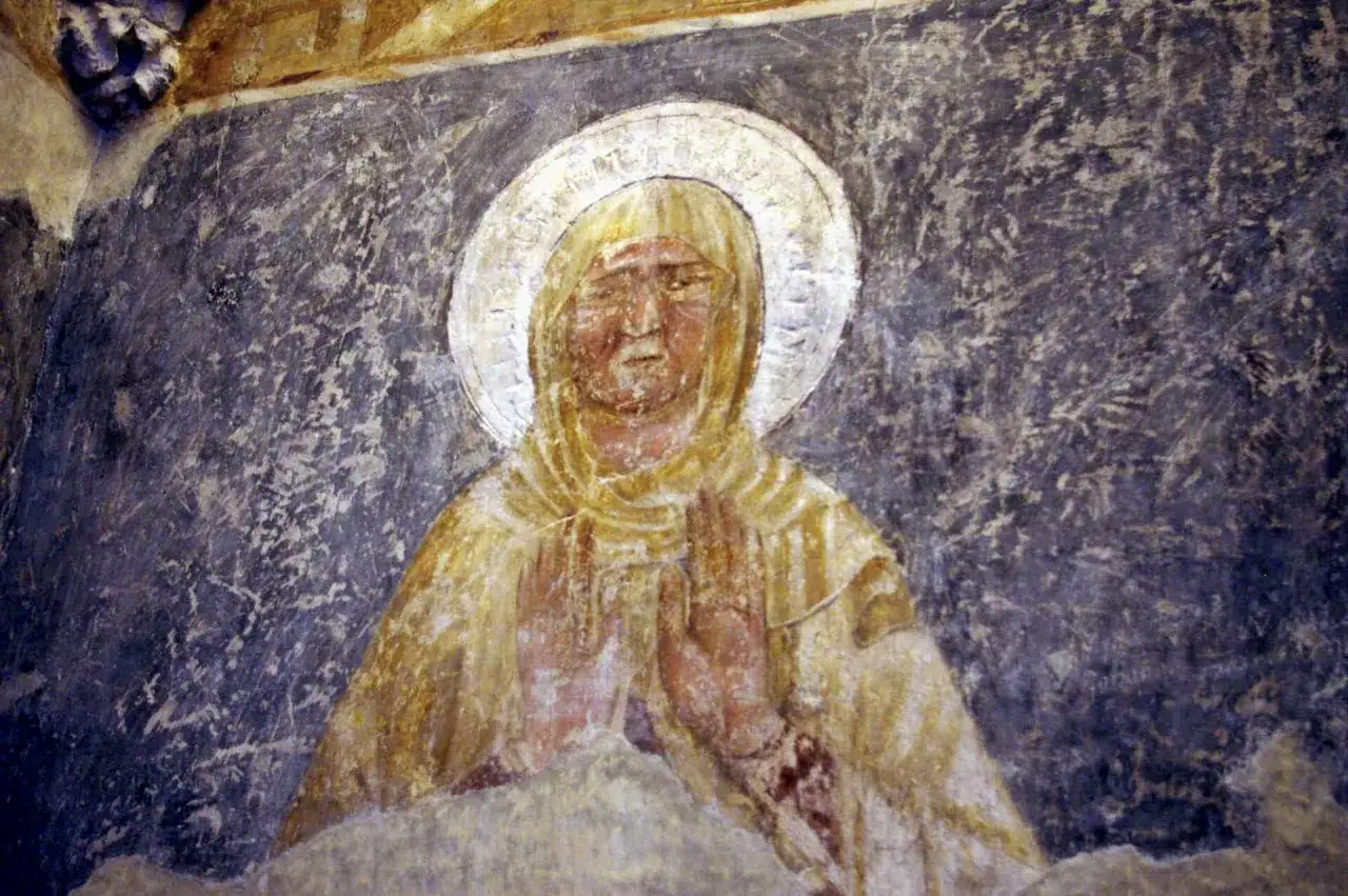 Fragment malarstwa gotyckiego: postać z aureolą, w żółtej szacie, z dłońmi złożonymi w modlitwie.